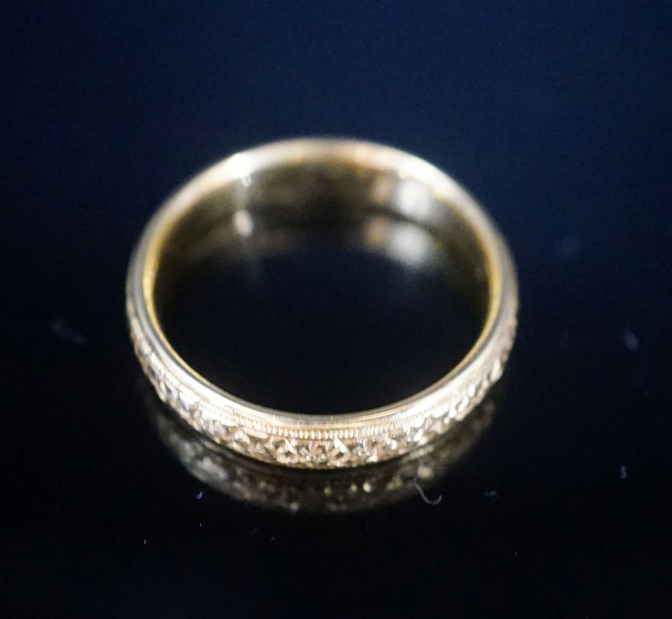 A George V bright cut engraved 22ct gold wedding band, decorate with flower heads, London, 1918, size V, 8 grams.